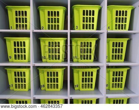 Plastic Boxes In Numbered Wooden Cells Of Shelving In A Checkroom