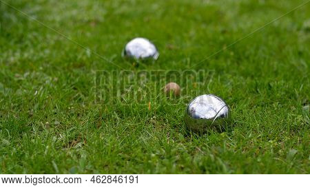 Close-up Of Steel Petanque Balls On A Green Lawn. Selective Focus. Petanque Balls Made Of Chrome-pla