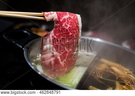 Hand Using Chopsticks Pick Premium Raw Beef Sliced Beef Over The Hot Pot Soup For Shabu Shabu Or Suk