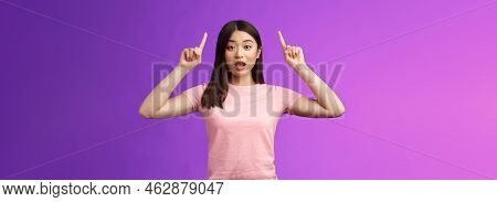 Excited Cute Surprised Asian Girl In Pink T-shirt Telling About Awesome News Pointing Raised Fingers