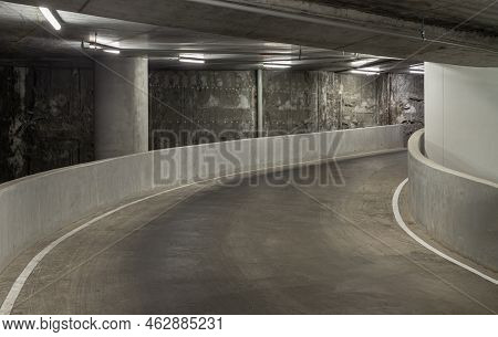 Way Down To Underground Car Parking. Perspective View Of Curving Shaped Ramp Of The Basement Made Of