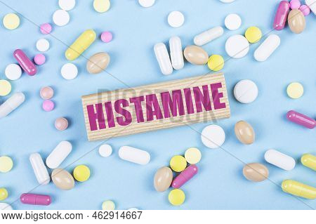 On A Blue Background, Multi-colored Pills And A Wooden Block With The Text Histamine. View From Abov