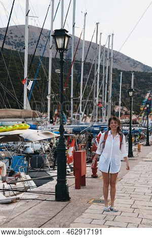 Smiling Caucasian Woman In Long White Beach Shirt Standing Near White Yachts For Rent At A Berth In 