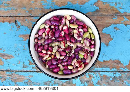 Defocus Purple Beans Background. Plate On Blue Background Of Many Grains Of Dried Beans. Brown Beans