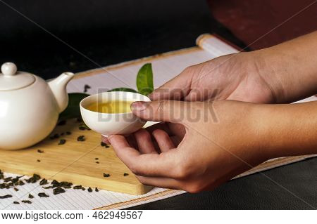 Hands Holding A Small Bowl Of Green Tea