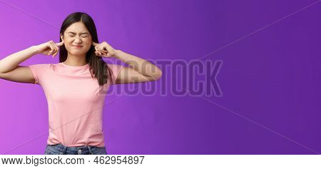 Displeased Annoyed Asian Brunette Woman Fed Up Hearing Loud Parents Yell, Close Eyes Grimacing, Plug