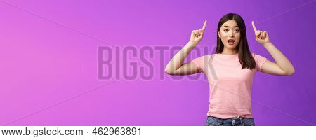 Excited Cute Surprised Asian Girl In Pink T-shirt Telling About Awesome News Pointing Raised Fingers