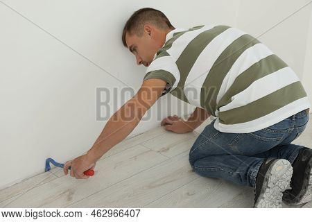 Professional Worker Using Nail Puller During Installation Of New Laminate Flooring Indoors