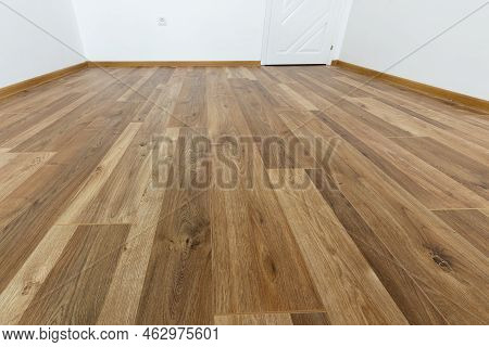 Laminated Wood Floor With White Wall. Empty Room With Floating Laminate In New Apartmen