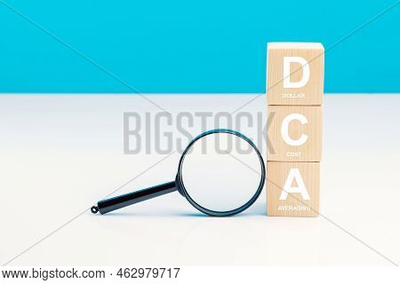Magnifying Glass And Dca Word On A Wooden Cube In Idea Dollar Cost Averaging Investment Strategy, Sa