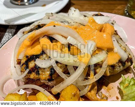 A Greek Dish With A Variety Of Meats, Chips And Onions.