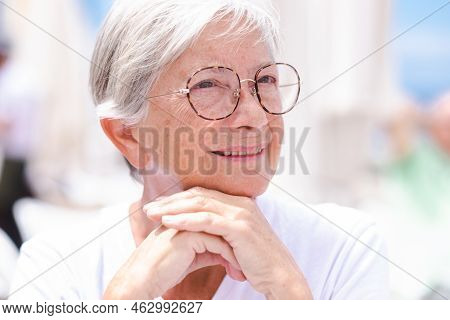Closeup Portrait Of A Beautiful Senior Caucasian Woman With Eyeglasses And Short White Hair Looking 