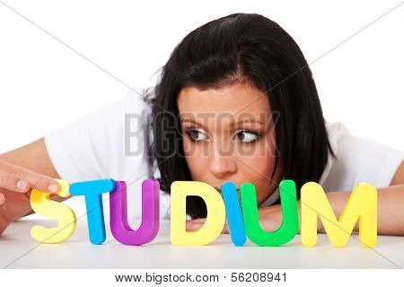 Young woman building the german term studium (eng. study) out of colorful letters.