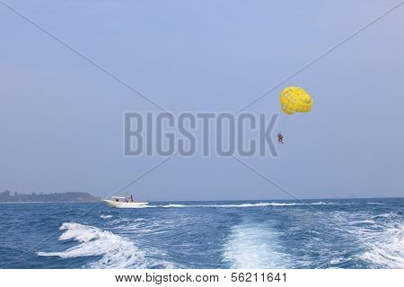 Two Of Young People Playing Parashoot Umbrella By Boat Pulling In Sea Water