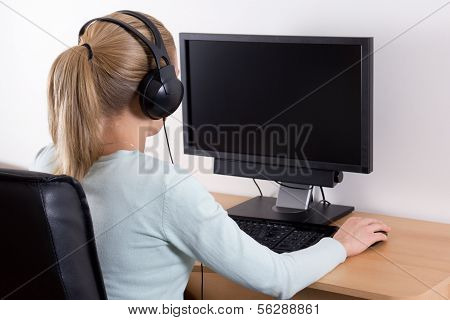 Back View Of Young Blondie Woman Using A Computer And Listening Music