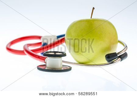 an apple and a stethoscope on a doctor. symbolic photo for healthy and vitamin-rich diet.