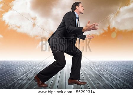 Businessman posing with arms outstretched against cloudy sky background
