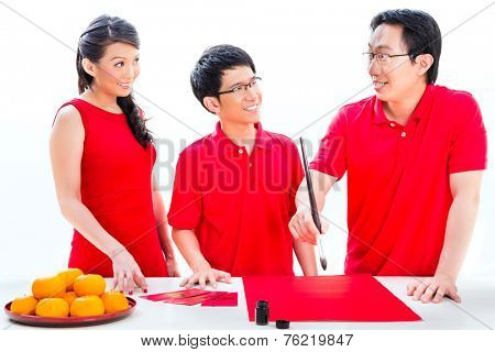 Friends family celebrate Chinese new year with traditional calligraphy, wearing red shirts