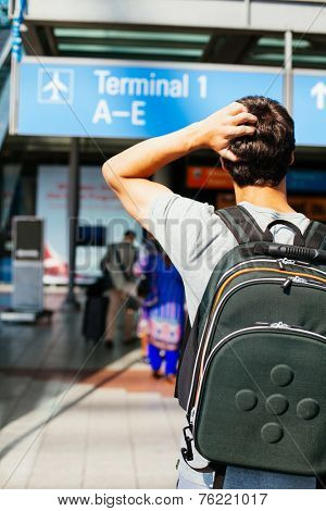 Confused young man with backpack looking for right direction in airport