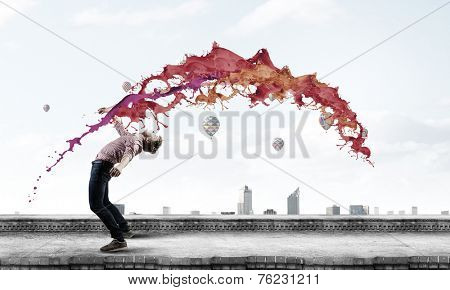 Young guy in casual evading from colorful splashes