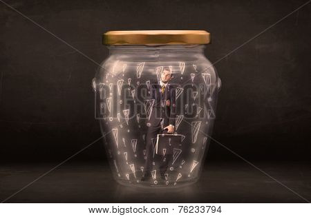 Business man trapped in jar with exclamation marks concept on bakcground