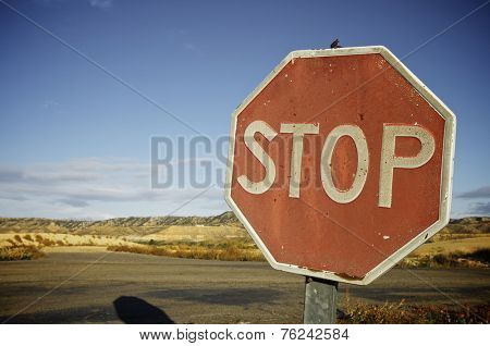 old and damaged stop sign against a blue sky