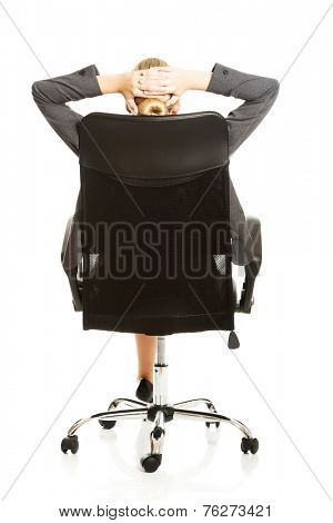Businesswoman resting on armchair holding her neck