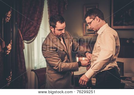 Tailor measuring client for custom made suit tailoring 