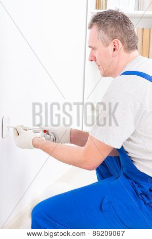 Electrician replacing old socket with pilers and screwdriver