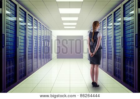 Redhead businesswoman with hands behind back against server room with towers
