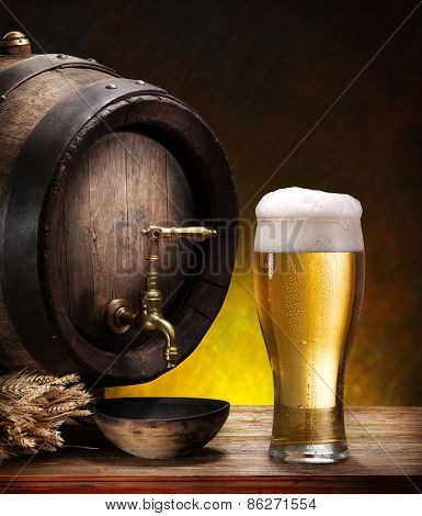 Still life: old wooden pin of beer, glass of beer and wheat on the table in the cellar.