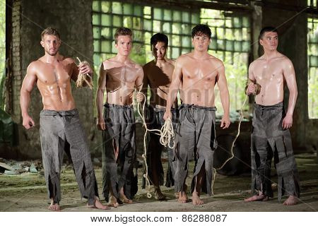 five young guys in ragged pants with ropes are in abandoned building 