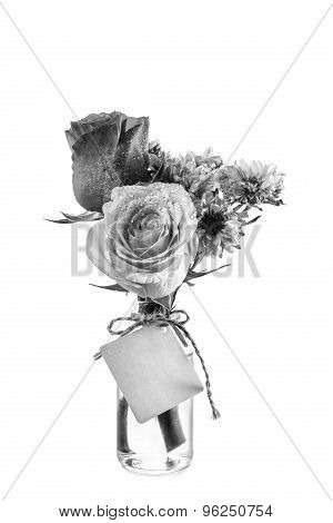 Blabk And White Flowers In Clear Bottle With Label On White Background
