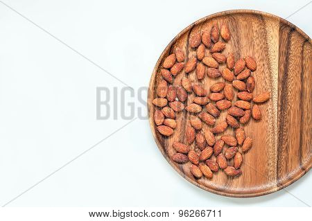 Salted & roasted almonds on wooden dish and white background