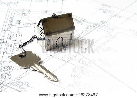 Small House Model Made Of Metal With A House Key On Architectural Drawing, Real Estate Concept