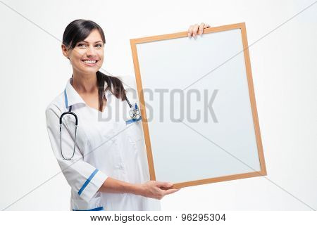 Smiling medical doctor holding blank board isolated on a white background. Looking at camera