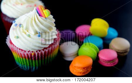 Colorful chocolate cupcake with vibramt macarons on black