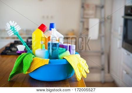 Basket With Cleaning Items On Blurry Background White Citchen. Cleaning Concept.