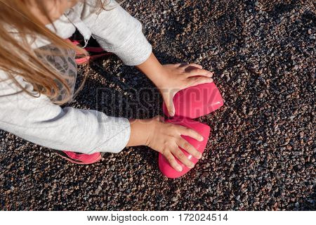 Little Girl Playing With A Red Plastic Heart. She Holds It In Her Hands
