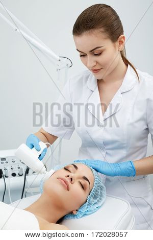 Brushing, brush-peeling. Brossage. Nozzle polishing stone. Model with closed eyes and doctor. Cosmetological clinic, procedure. Healthcare, clinic cosmetology