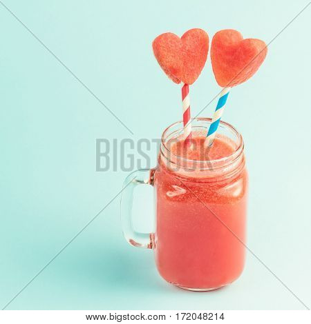 Watermelon smoothie in Mason jar with straws decorated with watermelon slices curved like heart symbols