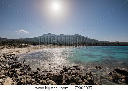 Deserted Bodri beach in the Balagne region of Corsica with the sun glaring down on the turqouise Mediterranean sea