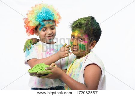 indian kids or boys playing with colours or asian children celebrating holi with pichkari - festival of colours