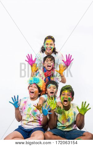 5 indian kids /friends /siblings celebrating Holi festival with and hands painted with gulal having copy space, isolated over white background