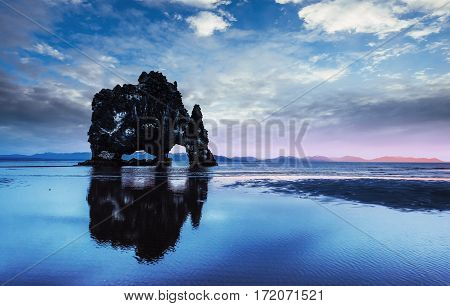 Hvitserkur is a spectacular rock in the sea on the Northern coast of Iceland. Legends say it is a petrified troll. On this photo Hvitserkur reflects in the sea water after the midnight sunset.