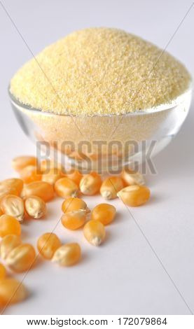 Corn flour and grains on white background. Isolated on white. Yellow powder in a glass bowl. Alternative gluten-free flour for baking and cooking.