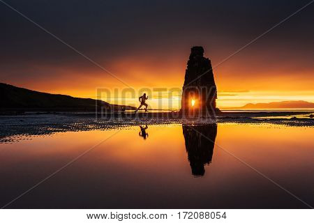 Hvitserkur 15 m tall. Spectacular rock in the sea on the north coast of Iceland. Legends say it petrified troll. In this photo Hvitserkur reflected in seawater after midnight sunset. Tourist runs.