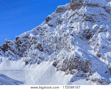 Mountain summit in the Swiss Alps, view from Mt. Titlis in winter ski piste and ski tracks on the snow. The Titlis is a mountain in Switzerland located on the border between Swiss cantons of Obwalden and Bern.