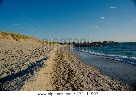 A sandy beach with tons of shells and crystal blue water - Horizontal