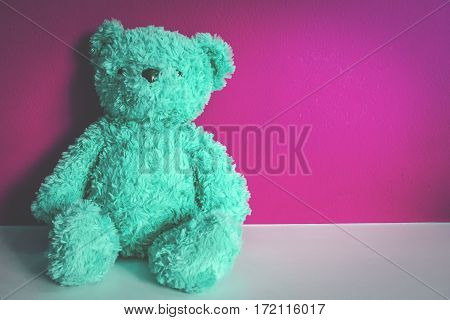 Teddy bear on white table with blue background.